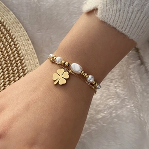 Détail d'un bracelet doré à plusieurs rangs avec perles et trèfle porté au poignet