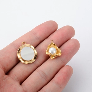 Irregular golden pendant with white shell pearl inlay held in hand for size reference