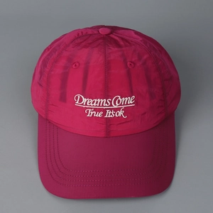 Detail of white embroidered text on quick-dry magenta nylon baseball cap surface