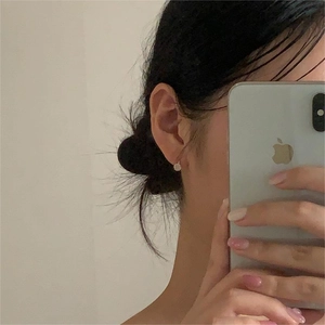 Close-up of minimalist white cat-eye floral stud earrings worn on a model