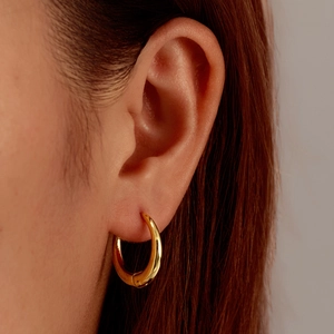Classic 18K gold plated round stainless steel hoop earrings on a female model