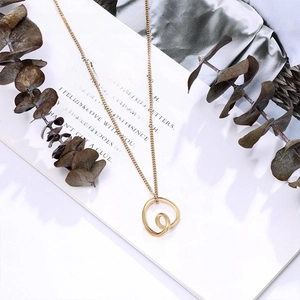 Detailed shot of a twisted gold circular pendant on a sleek titanium steel chain