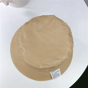 Detailed view of the khaki bucket hat with a flat top and stylish white logo patch