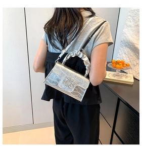 Detail of silver crocodile pattern handbag with crystal buckle worn by a model