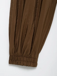 Close-up of brown safari pants showing elastic cuffs and shiny pleated fabric details