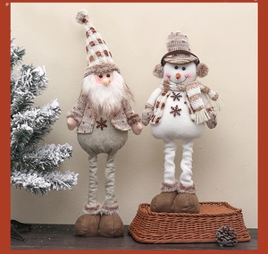 Detail von gestrickten Weihnachtsmann- und Schneemannpuppen mit Teleskopbeinen auf Holz