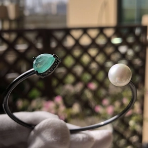Classic open bangle with green teardrop gemstone and white pearl on black metal ring