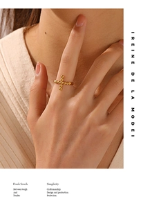 Nahaufnahme eines verstellbaren goldenen Perlenkreuz-Rings an einem Model in Beige