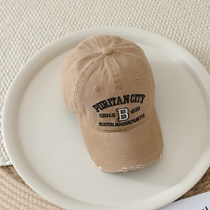 Close-up of khaki baseball cap featuring distressed brim and black 3D embroidery