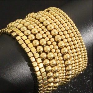 Detail of stacked gold beaded and geometric link bracelets on black display stand