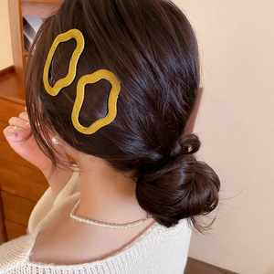 Detail view of two yellow flocked irregular wave hair clips worn on side of hair