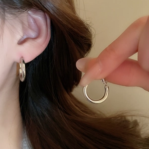 Detailed view of silver hoop earrings worn on ear showing polished finish and style