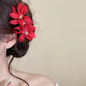 Detail of red fabric flower hair pin with dewdrop accents on a classic updo