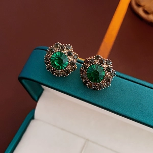 Macro shot of vintage French style green flower stud earrings with crystals on a jewelry box