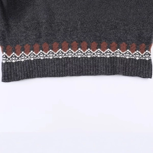 Close-up of dark grey knit sweater with jacquard geometric pattern and ribbed hem