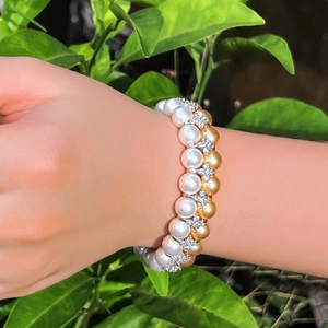 Double-layer pearl bracelet with micro-pave zircons worn on wrist with leaf background