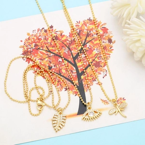 Detailed close-up of gold beaded necklaces featuring feather, evil eye and dragonfly charms