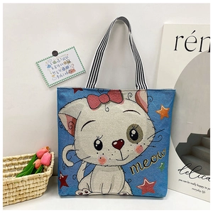 Detail of blue tote bag with white cartoon cat print and yellow meow embroidery