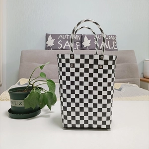 Detail of hand-woven black and white checkered tote bag with silver metal rivets
