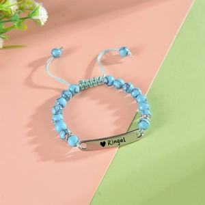 Détail des perles turquoise et de la plaque en acier inoxydable gravée pour bracelet bébé