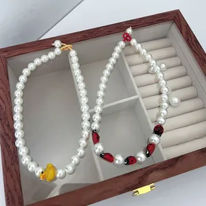 Detail of colorful beaded necklaces with yellow duck and ladybug charms in a wooden jewelry box