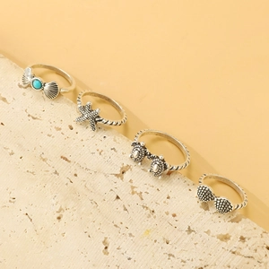 Détail d'un ensemble de bagues vintage avec tortue marine, étoile de mer et breloques turquoise