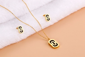 Detail of gold paperclip chain necklace and earrings set with black oval inlays