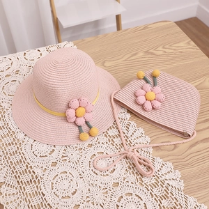 Ensemble chapeau de paille rose et sac à fleurs pour fille sur nappe en dentelle
