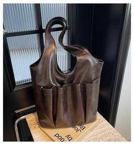 Detail of soft brown leather tote bag with pleated texture and multiple pockets