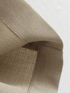 Macro detail of high-quality light khaki linen fabric texture and flat hem stitching