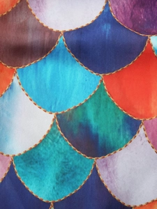 Close-up of vibrant mermaid scale print fabric with golden outlines and gradient colors