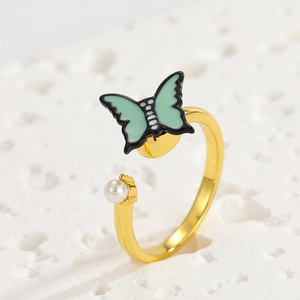 Detail of adjustable gold ring featuring a green enamel butterfly and a white pearl