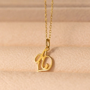 Polished gold initial A pendant necklace on a beige leather texture jewelry box