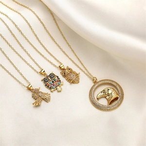 Detail of gold-plated necklaces with colorful zircon owl and eagle pendants on white silk