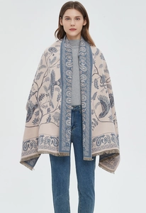 Macro shot of paisley floral scarf with tassels in beige and blue hues on a model