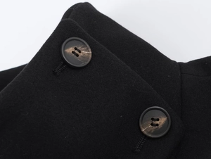 Detail view of black woolen coat fabric with two brown marble texture buttons