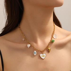 Makroaufnahme einer Goldkette mit Anhängern aus Muscheln, Herzen und blauen Augen
