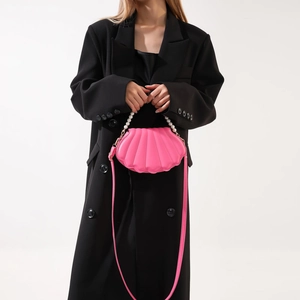 Pink shell crossbody bag detail featuring pearl chain strap and PU leather on black coat