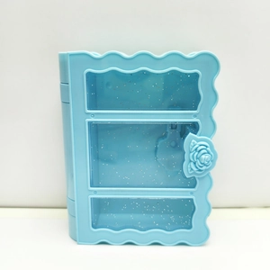 Blue book-shaped plastic jewelry box with three glittery compartments and a rose clasp