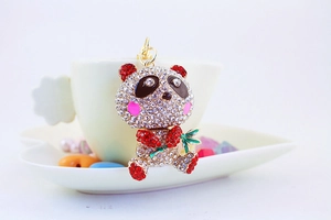 Macro shot of a crystal panda keychain with colorful rhinestones in a white ceramic dish