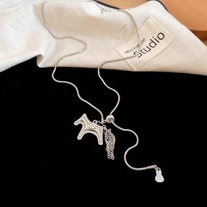 Detailed view of silver snake chain necklace with zircon horse pendant and metal tassels