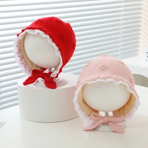 Detail of baby knit earflap hats with white lace trim and decorative ribbon ties