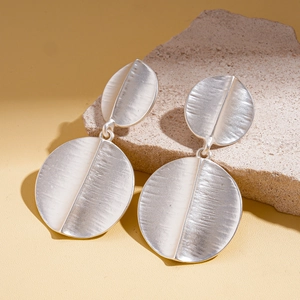 Macro view of geometric silver earrings with brushed metallic texture on stone