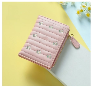 Detail of pink quilted short wallet for women with delicate floral embroidery and gold zipper