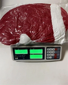Détail d'un coussin en forme de bonnet de Noël rouge pesant 0,296 kg sur une balance