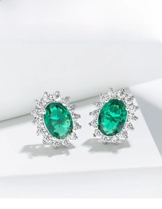 Close-up of oval emerald-style stud earring with sparkling white zircon halo on white display