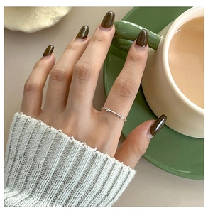 Close-up of a minimalist silver hollow bow ring worn by a model in a cozy cafe setting