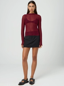 Full view of a wine red sheer hollow-out long sleeve top with a black mini skirt