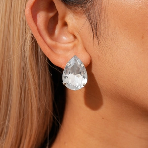 Close-up of teardrop-shaped crystal earrings with silver-tone prong setting on model