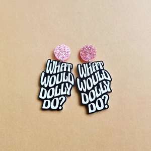 Detail of What Would Dolly Do acrylic earrings with pink glitter studs on khaki card